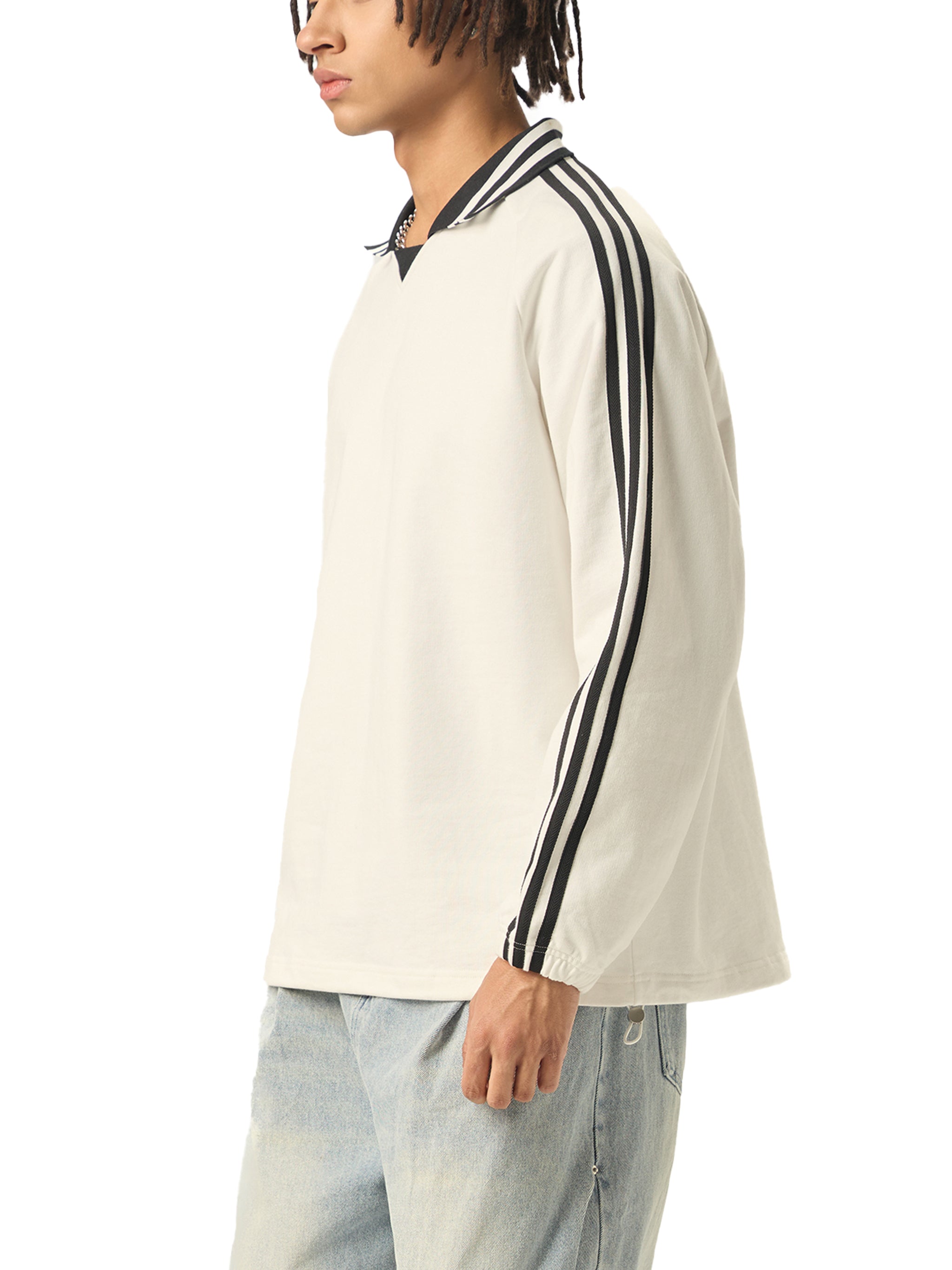 Man wearing an oversized white long sleeve shirt with black stripes and light blue jeans