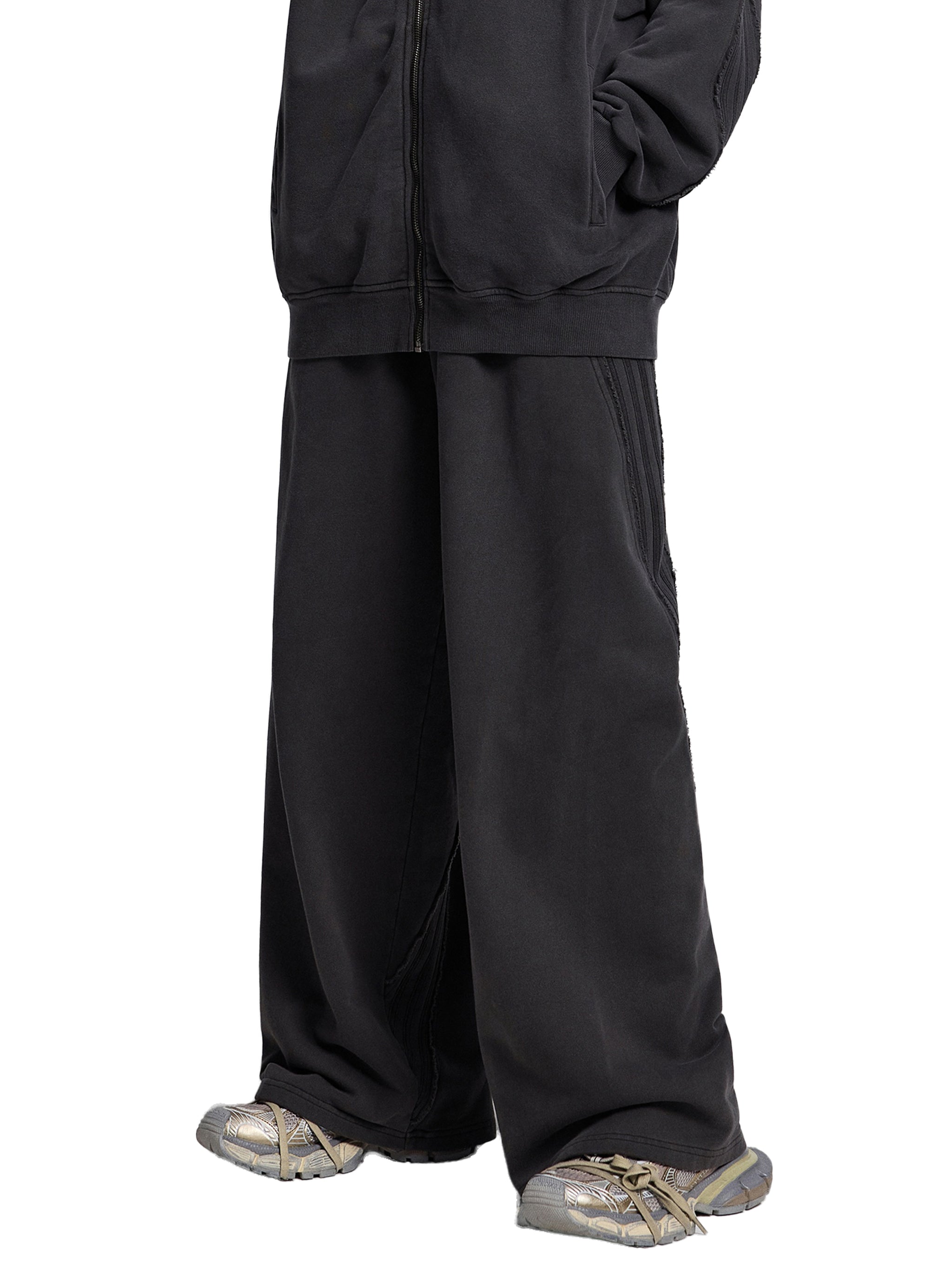 Oversized black wide-leg streetwear pants styled with silver sneakers on white background