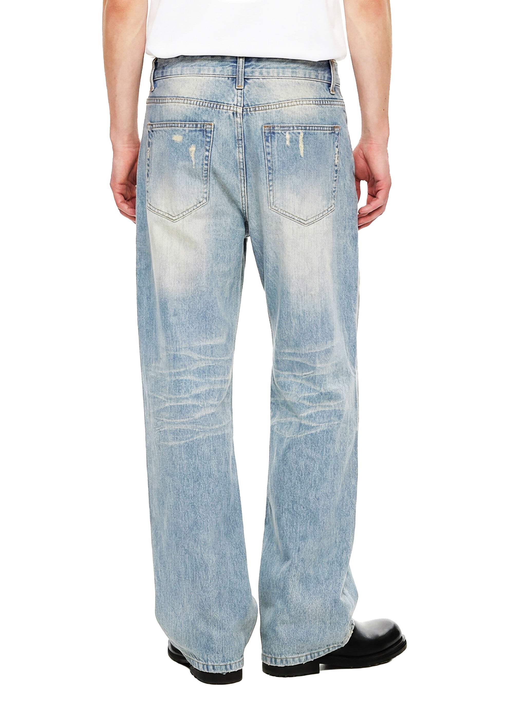 Back view of man wearing faded light blue relaxed fit jeans with distressed pockets
